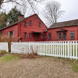 a house with a fence in front of a brick building