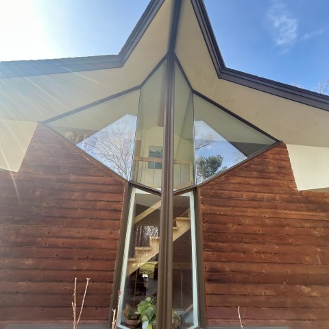 A-frame house with large triangular windows and wood siding under a clear blue sky.