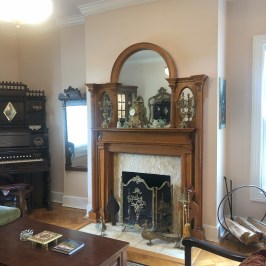 Vintage living room with fireplace, ornate mirror, and organ.