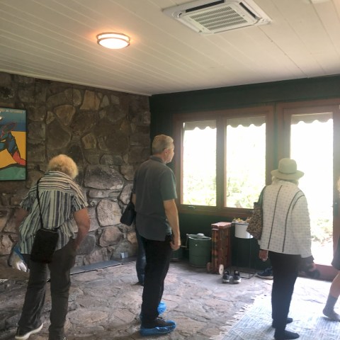 People standing in an indoor room with stone walls and large windows.
