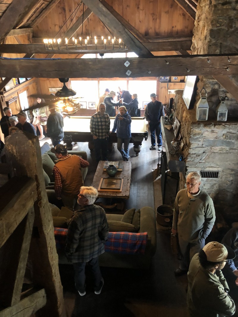 People socializing in rustic room with pool table and stone walls.