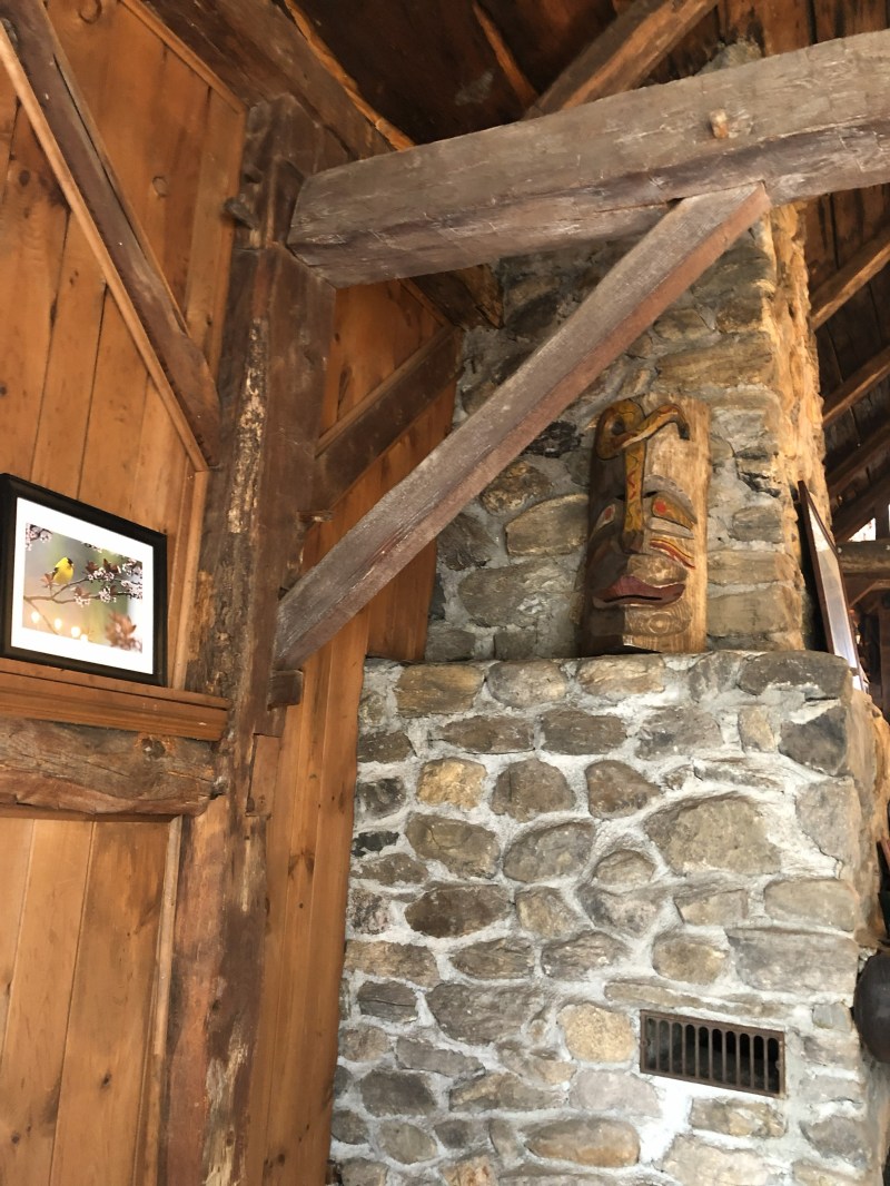 Wooden beams with stone wall and framed photo; decorative mask mounted on wall.