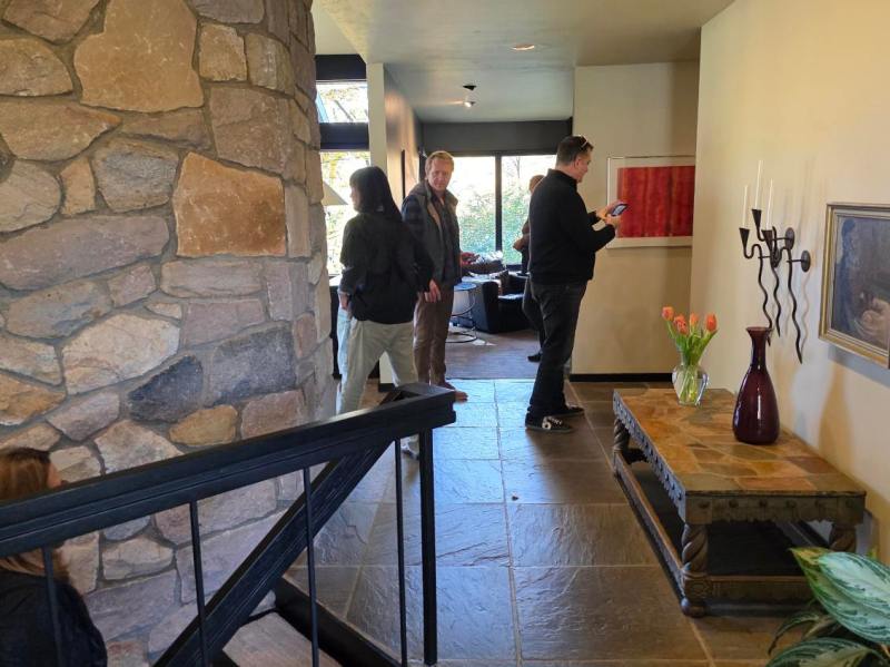 People standing in a living room with stone wall, table, and artwork.