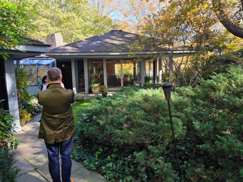Person taking photo of modern house with garden and large windows.