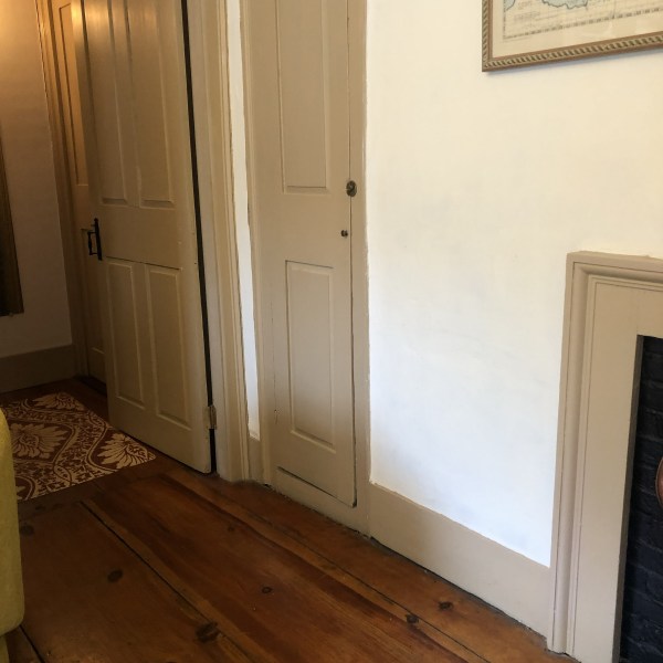 Cozy room corner with wooden floor, beige doors, and framed map on wall.