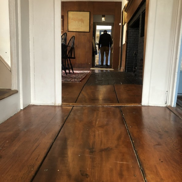 Interior with wooden floor, open door at end, person standing by doorway.